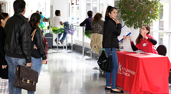 Student asking a Student Ambassador at a welcome desk for directions